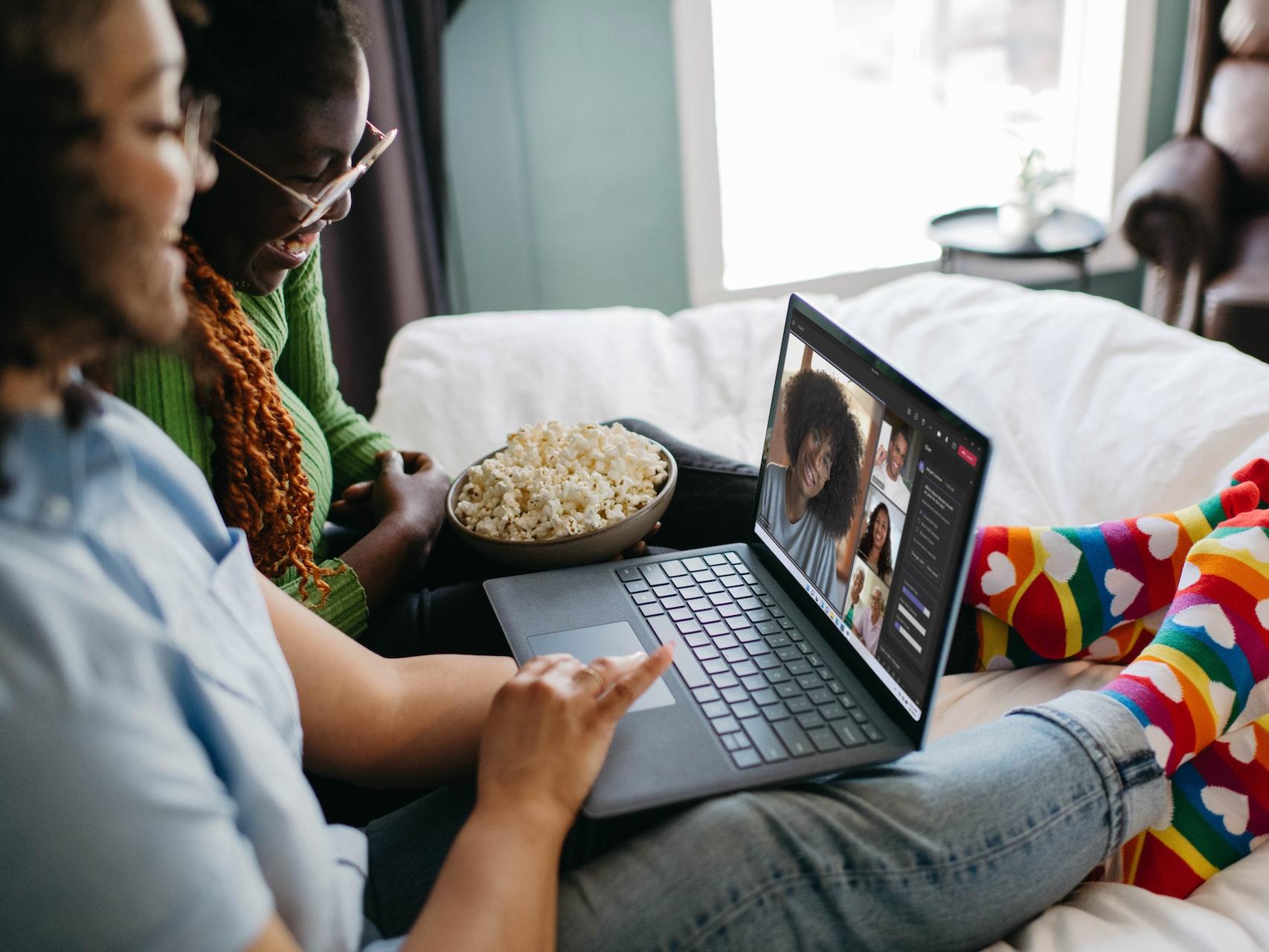 Una pareja de personasl sentadas en una cama con una laptop